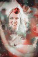 Composite image of festive blonde hanging bauble on christmas tr