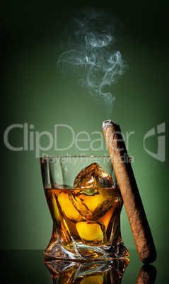Whiskey and cigar on green