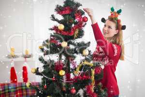 Composite image of young woman decorating a christmas tree