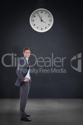 Composite image of smiling businessman with hands on hips