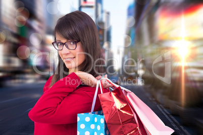 Composite image of happy brunette holding shopping bags