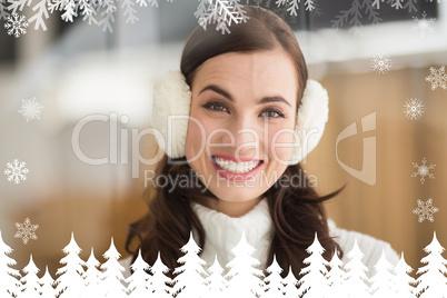 Composite image of beauty brunette with ear muffs smiling at cam