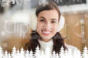 Composite image of beauty brunette with ear muffs smiling at cam