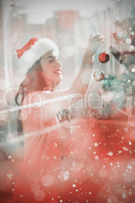 Composite image of festive brunette decorating a christmas tree