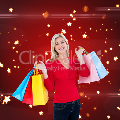 Composite image of happy blonde holding shopping bags