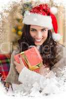 Composite image of festive brunette pressing gift at christmas