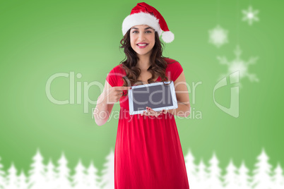 Composite image of festive brunette pointing her tablet