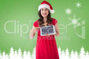 Composite image of festive brunette pointing her tablet