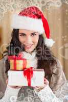 Composite image of festive brunette in santa hat holding gifts