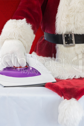 Composite image of father christmas is ironing his hat