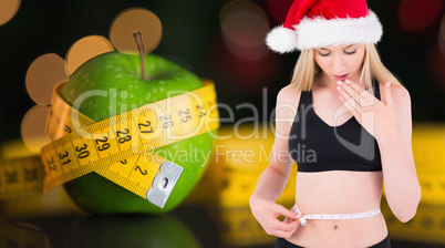 Composite image of fit festive young blonde looking at measuring