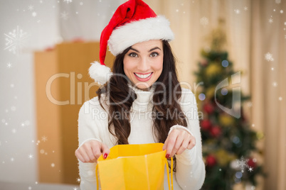 Composite image of festive brunette opening gift bag