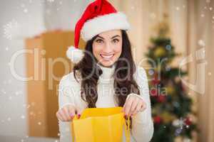 Composite image of festive brunette opening gift bag