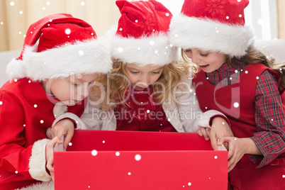 Composite image of festive little siblings looking at gift