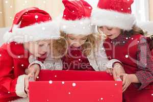 Composite image of festive little siblings looking at gift