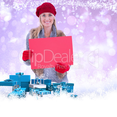 Composite image of blonde in winter clothes holding red sign