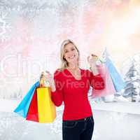 Composite image of happy blonde holding shopping bags