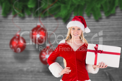 Composite image of festive blonde holding a gift