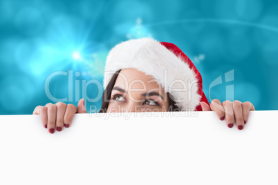 Composite image of pretty brunette in santa hat showing white po