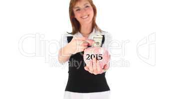 Composite image of woman putting money in a piggy bank