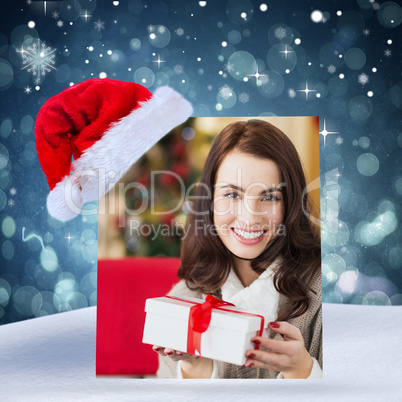 Composite image of smiling brunette holding gift on the couch at