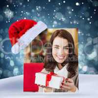Composite image of smiling brunette holding gift on the couch at