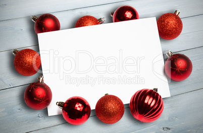 Composite image of red christmas baubles surrounding white page