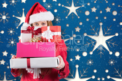 Composite image of festive redhead holding pile of gifts