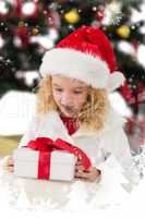 Composite image of festive little girl looking at gift