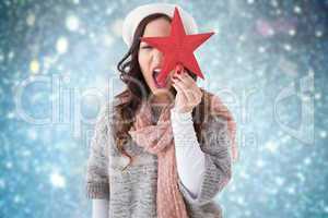 Composite image of excited brunette in winter clothes holding st