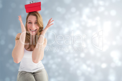 Composite image of smiling woman balancing christmas gift on her Composite image of smiling woman balancing christmas gift on her