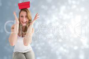 Composite image of smiling woman balancing christmas gift on her