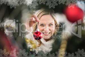 Composite image of festive blonde hanging bauble on christmas tr