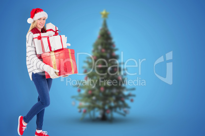 Composite image of festive blonde holding pile of gifts