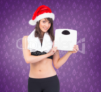 Composite image of festive fit brunette holding weighing scales