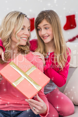 Composite image of little girl giving her mother a christmas gift Composite image of little girl giving her mother a christmas gift