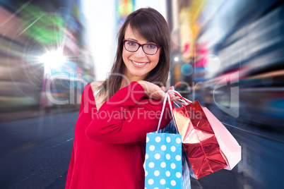 Composite image of smiling brunette holding shopping bags