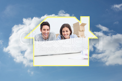 Composite image of couple lying on the floor and holding a house