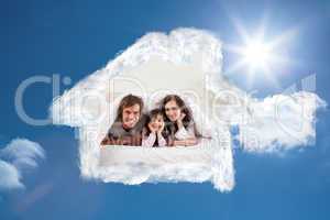 Composite image of smiling parents lying under a duvet with thei