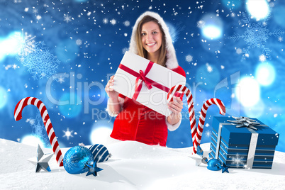 Composite image of pretty santa girl holding gift