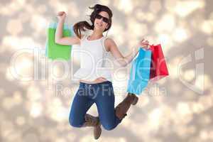 Composite image of happy brunette jumping with shopping bags