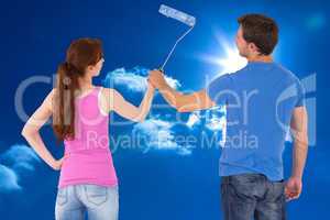 Composite image of couple painting a wall together