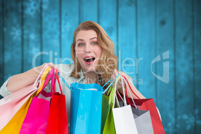 Composite image of overwhelmed young woman with shopping bags