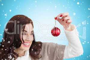 Composite image of pretty brunette holding bauble