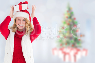 Composite image of smiling woman balancing christmas gift on her