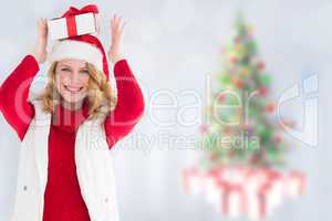 Composite image of smiling woman balancing christmas gift on her