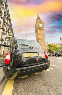 Black London cab under Big Ben tower and Westminster Palace