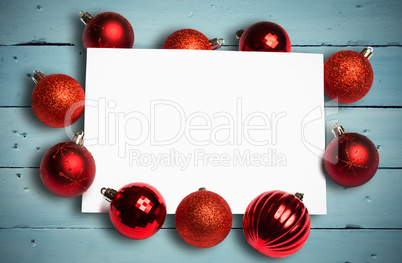 Composite image of red christmas baubles surrounding white page