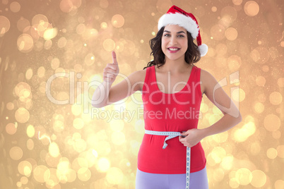 Composite image of festive fit brunette measuring her waist
