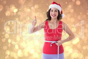 Composite image of festive fit brunette measuring her waist